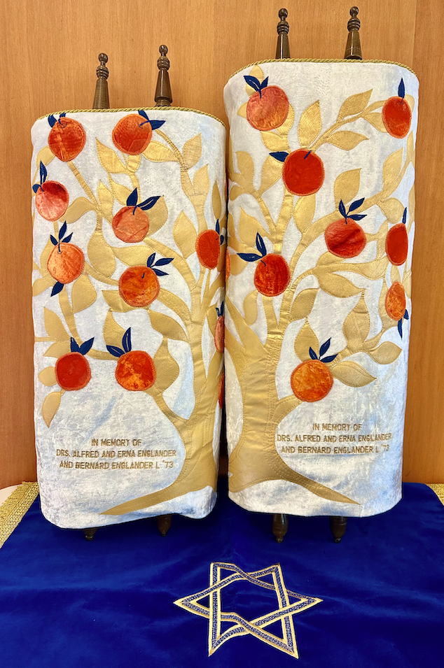 The Torah scrolls are shown with their new covers. The gold Tree of Life is depicted and laden with oranges.